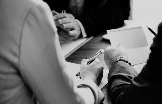 Grayscale photo of hands in a business meeting.
